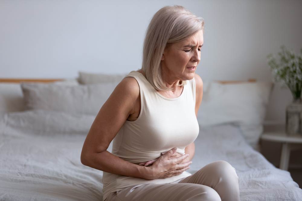 older woman holding her stomach because it is hurting